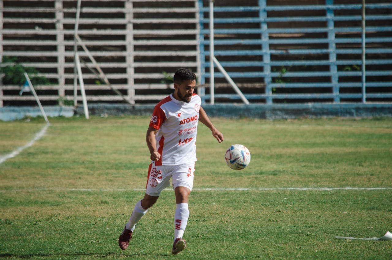 Soccer player in white kit playing on a field in Mendoza, Argentina.